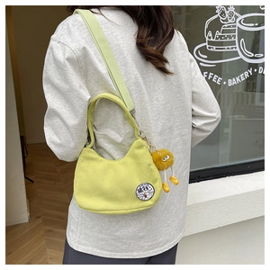 Détail du sac en velours côtelé vert clair avec patch canard et pendentif en peluche