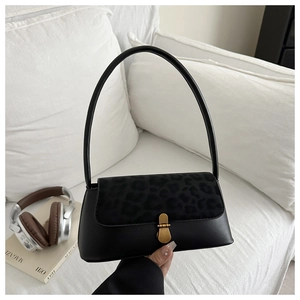 Detail shot of black leather baguette bag with leopard print flap and gold clasp