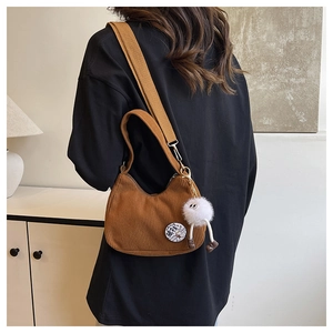 Détail d'un sac bandoulière en velours côtelé marron avec pendentif en peluche