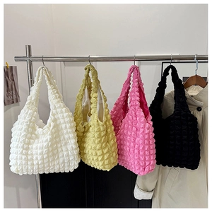 Detail of colorful bubble textured tote bags in white, yellow, pink, and black