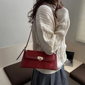 Minimalist red leather patchwork baguette bag with gold lock worn by model