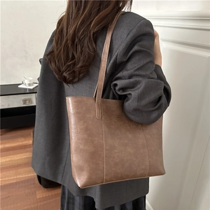Brown faux leather tote bag with large capacity and shoulder straps shown on model