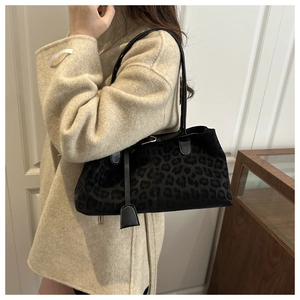 Detailed view of leopard print shoulder bag worn with a beige wool coat in a stylish setting