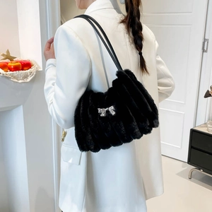 Elegant black faux fur shoulder bag with silver bow detail worn by a model in white blazer