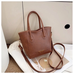 Detailed shot of dark brown textured leather bucket bag with gold logo and round handles