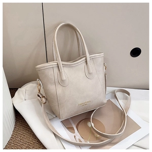 Detail of beige faux leather bucket bag with Fashion & BAG EST 1985 text and gold hardware