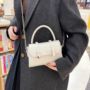 Minimalist cream PU leather mini handbag with gold chain strap shown on a tweed coat