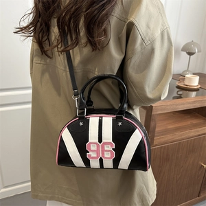 Women's black striped bowling bag with pink trim and number 96 patch in a modern room