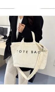 Detail of off-white corduroy tote bag showing embroidered letters and ribbed texture