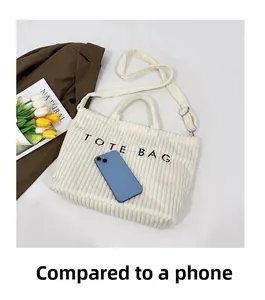 Detail of off-white corduroy tote bag showing striped texture compared to a mobile phone