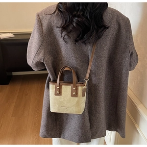 Detail view of mini two-tone leather tote bag featuring beige suede and brown straps