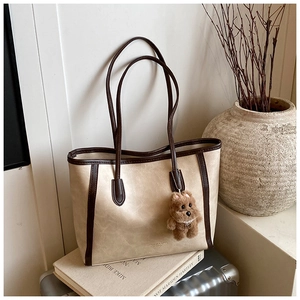 Détail d'un sac cabas beige à texture marbre avec un charme de chien en peluche marron