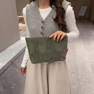 Trousse de toilette en velours côtelé vert armée tenue par un mannequin