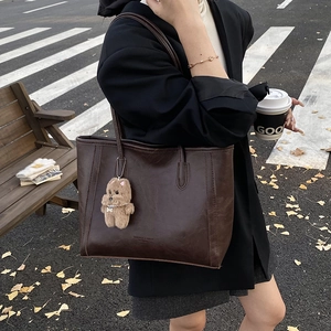 Grand sac cabas marron foncé avec breloque ours porté par un mannequin dans la rue