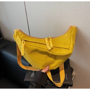 Dettaglio borsa a mezzaluna in nylon giallo con tiri a corda intrecciata e tracolla larga