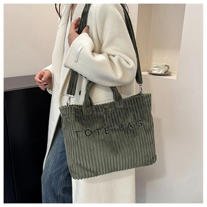 Detail of green corduroy tote bag showing textured fabric and embroidered letters