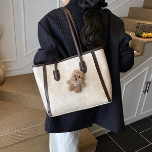 Grand sac cabas rétro beige avec anses brunes et breloque ours porté par un mannequin