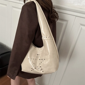 Borsa a spalla color crema con borchie a stella indossata da una modella