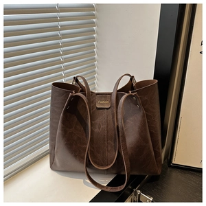 Detail of deep brown oil-wax leather tote bag showing rich texture and gold fashion buckle