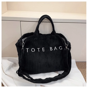 Detail of black corduroy tote bag showing embroidered text and soft ribbed texture