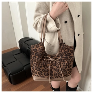 Détail du sac cabas léopard avec anses en cuir et nœud décoratif sur le modèle