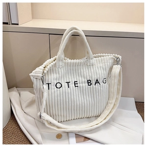 Detail of white corduroy tote bag showing embroidered text and vertical ribbed texture