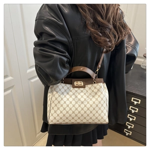 Detail of vintage triomphe pattern handbag with brown leather trim and golden twist lock