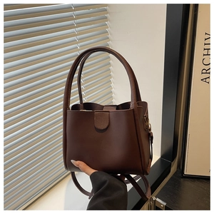 Detail view of smooth dark brown bucket tote bag with round handle and leather shoulder strap