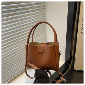 Detail of caramel faux leather tote showing double handles and magnetic clasp flap