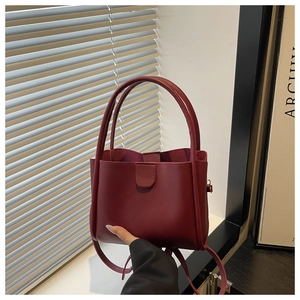 Close-up of a burgundy leather bucket bag with top handles and a magnetic closure detail