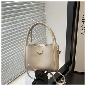 Detail of minimalist cream leather bucket bag with semi-circular buckle and double handles