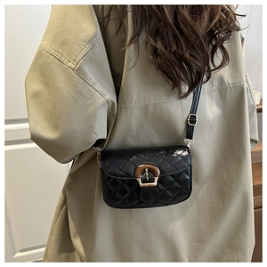 Close-up of a quilted black crossbody bag with a decorative tortoiseshell buckle