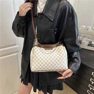 Retro monogram crossbody bag with top handle and brown leather trim in home setting
