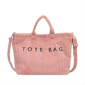 Pink corduroy tote bag with black embroidery and adjustable shoulder strap on white background