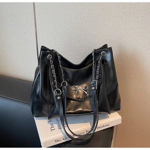 Detail of black tote bag with silver metal bow and chain leather shoulder strap