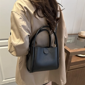 Retro black leather bucket bag with top handles and cross-body strap for daily commute