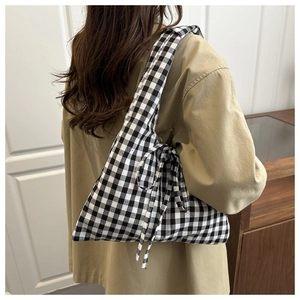 Detail of a chic black and white checkered tote bag with a decorative side bow knot
