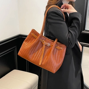 Brown woven leather tote bag with long handles shown on model in a minimalist setting