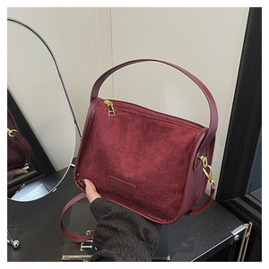 Detail view of burgundy suede and leather bag with round handle and gold hardware