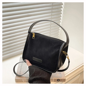 Detail of black matte suede and smooth leather texture with gold-tone hardware