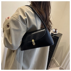 Detail of vintage black baguette bag with gold metal lock on beige trench coat