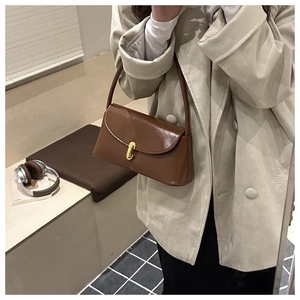 Brown retro baguette shoulder bag with gold metal buckle worn with casual blazer