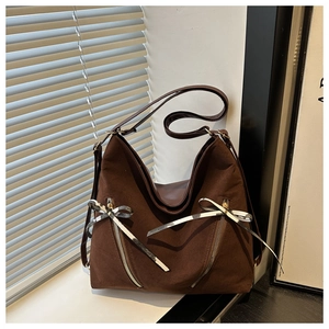 Detail of dark brown hobo bag featuring bow-tied ribbons and dual front zipper pockets