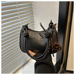 Détail du sac hobo noir avec poignée en nœud de corde et breloques décoratives