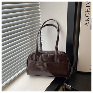 Detail showing high-gloss brown faux leather texture and front pocket of the shoulder bag