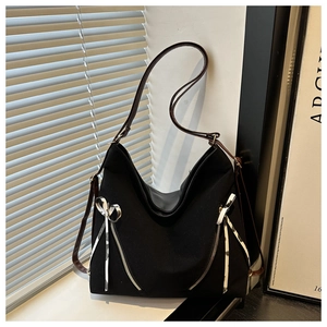 Detail of black large canvas hobo bag featuring decorative zippers and white silk bows