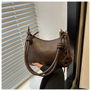 Détail du sac demi-lune marron vintage avec poignées à nœuds et lettrage doré