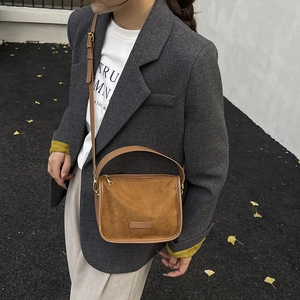 Brown frosted suede crossbody bag with gold zippers shown on a street style model