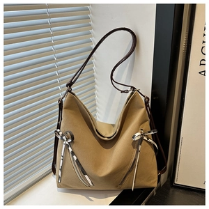 Detail of khaki tote bag with symmetric silver zippers and satin bow accents