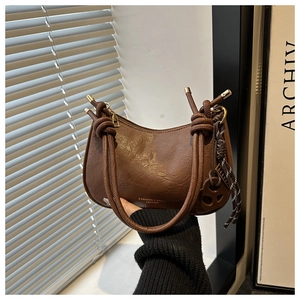 Gros plan du sac hobo marron avec bandoulière nouée et pendentif tissé détaillé